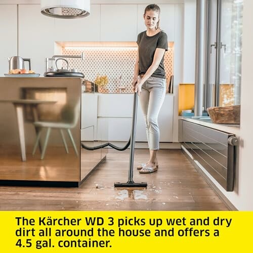 Woman using Kärcher WD 3 vacuum on kitchen floor.