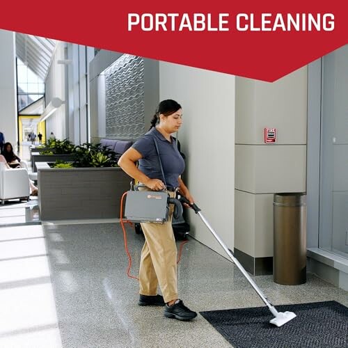 Person using a portable cleaning device in a modern building